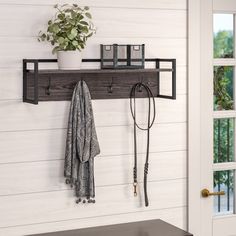 a wall mounted coat rack with two hooks and a hat hanger on the top