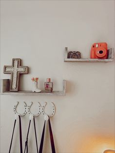 the wall is white and has three wooden shelves with cross decorations on them, along with other items