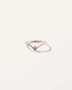 a gold ring with a diamond on the top and an arrow shaped band, against a white background