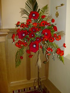 a bouquet of red flowers in a vase on a stand next to a door way