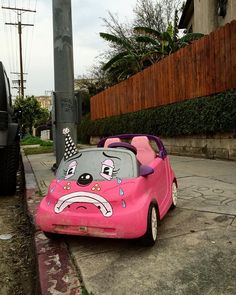 a pink toy car with an angry face painted on it's side sitting in the street