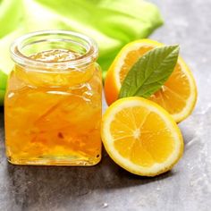 a glass jar filled with liquid next to sliced oranges and green leafy leaves