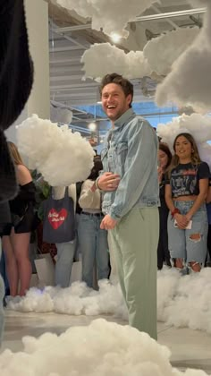 a man standing in the middle of a cloud filled room with people looking at him