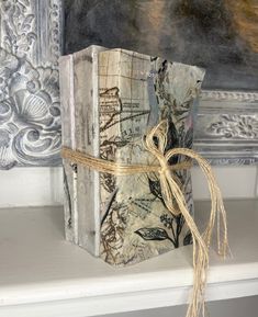 an old book wrapped in twine and tied with a brown ribbon sitting on top of a white mantle