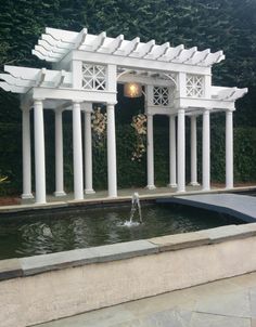 an outdoor fountain with white pillars and flowers