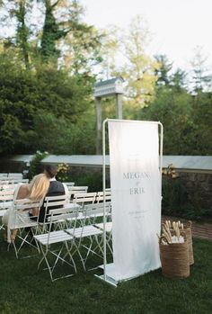 two people sitting on white chairs next to each other in front of an outdoor ceremony