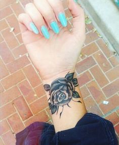 a woman's arm with a rose tattoo on it and a brick wall in the background