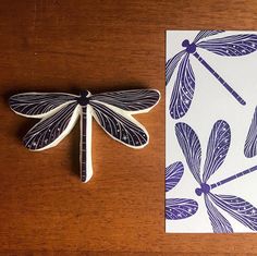 a dragonfly is sitting on top of a card next to it's shadow