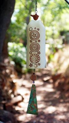 a wind chime hanging from a tree in the woods with an intricate design on it