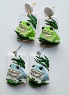 four frog earrings with green leaves on them