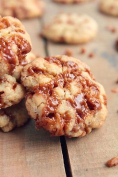 two cookies with caramel toppings sitting on top of a wooden table next to other cookies