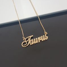 a gold necklace with the word taurus written in cursive font on it