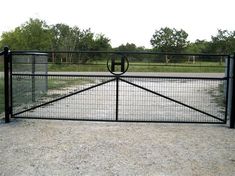 an iron gate with a circle at the top and bottom, in front of a field