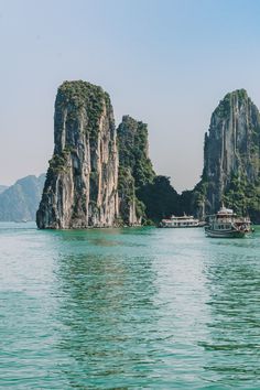 a boat is in the water near some large rocks and small island with houses on them