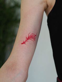 a woman's arm with a red tattoo on the left side of her arm