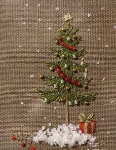 a small christmas tree on top of cotton in front of a burlap background