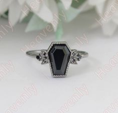 a black and white diamond ring sitting on top of a table next to some flowers