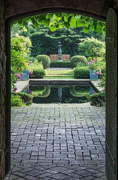 an open door leading to a garden with a pond and bench in the middle of it