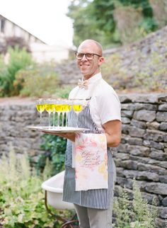 a man in an apron holding a tray with drinks