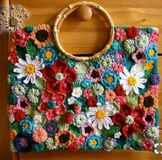 a crocheted bag with flowers on it sitting on a wooden table next to a door