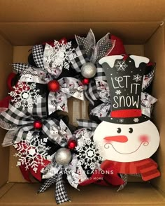 a christmas wreath in a box with snowman decorations on it and the words let it snow