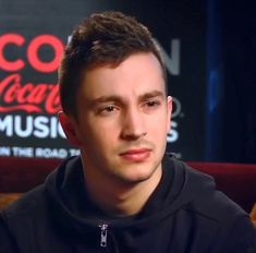 a man sitting in front of a coca cola sign with his head turned to the side