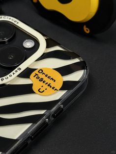 a close up of a cell phone on a table with headphones in the background