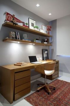 a desk with a laptop on top of it and shelves above the desk in front of it