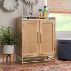 a wooden cabinet sitting on top of a rug next to a potted green plant