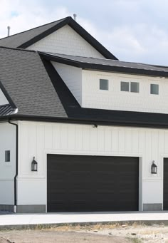 a white house with two black garage doors