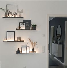 some shelves with pictures and candles on them in a room that is decorated with white walls