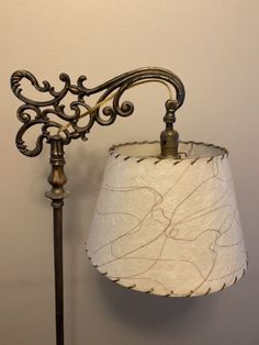 a lamp that is on top of a table next to a wall with a white shade