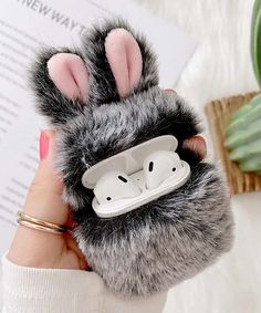 a person holding up a cell phone case with ear buds in the shape of a rabbit's paw