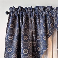 the curtain is hanging on the wall next to an open window with blue and white patterned curtains