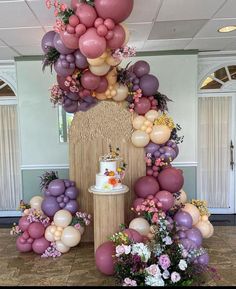 a table topped with lots of balloons and flowers next to a cake on top of a pedestal