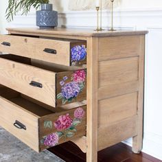 a wooden dresser with flowers painted on the drawers