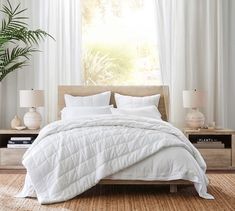 a bed with white comforter and pillows in a bedroom next to a plant on a table