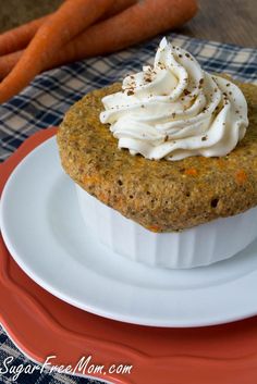 a carrot cake with whipped cream on top sits on a plate next to some carrots