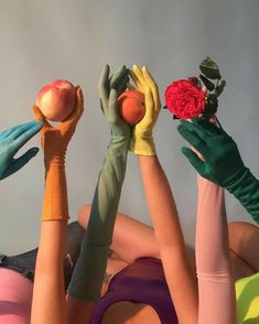 four hands reaching up to grab an apple