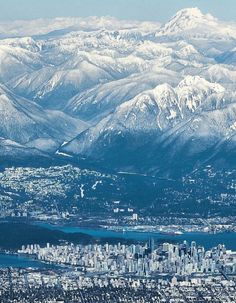 an aerial view of the city and mountains in winter, with snow - capped peaks