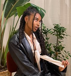 a woman sitting on a chair in front of a plant