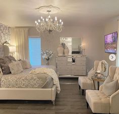 a bedroom with a chandelier hanging from the ceiling next to a bed and two chairs