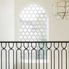 an iron railing in front of a large window with a chandelier hanging above it