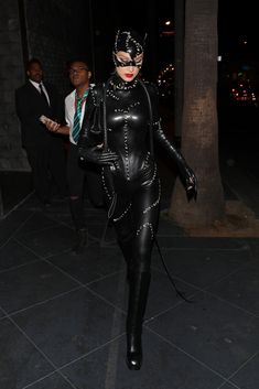 a woman in black catsuit walking down the street