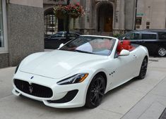 a white masera is parked on the side of the street in front of a building