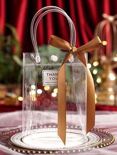 a clear bag with a brown ribbon on top of a glass plate that says thank you