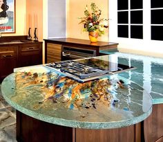 a kitchen with a glass counter top that has fish swimming in the water on it