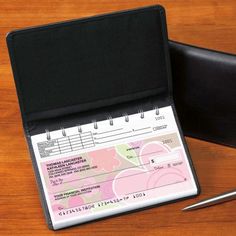 a notepad and pen sitting on top of a wooden table next to a wallet