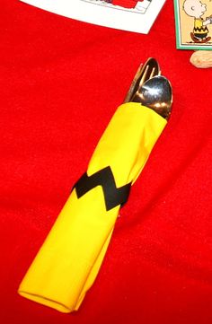 a yellow and black fork sitting on top of a red table cloth next to a book