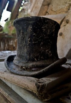 black and white photograph of an old top hat sitting on a piece of wood in the middle of a room